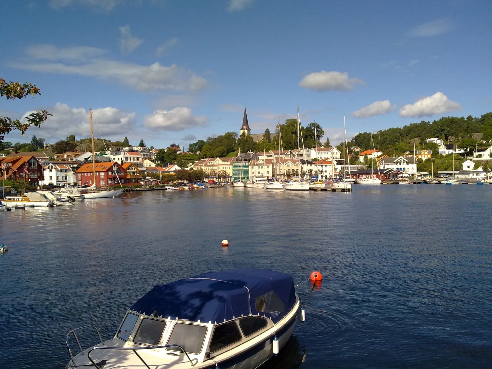 Grimstad havn med seilbåter og kirken på Kirkeheia over byen
