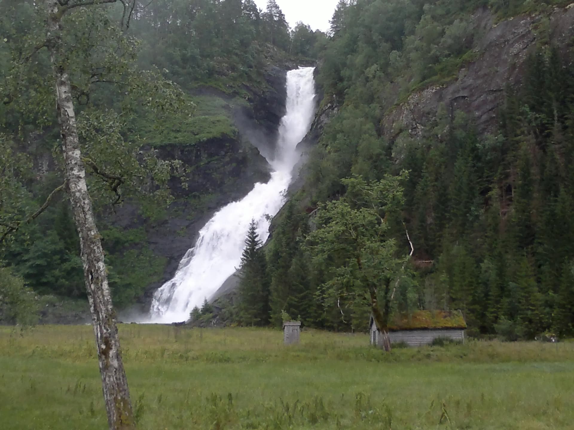 Huldefossen i Sunnfjord med torvtekt stabbur ved foten av fossen