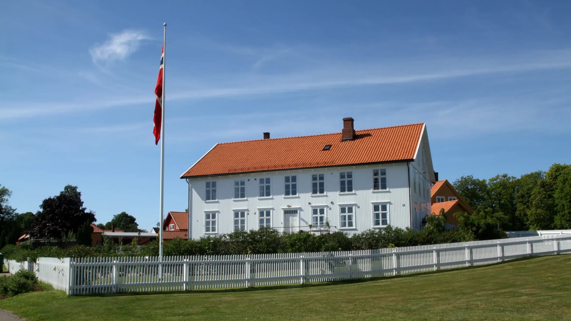 Karljohansvern i Horten — hvit trebygning med norsk flagg en sommerdag