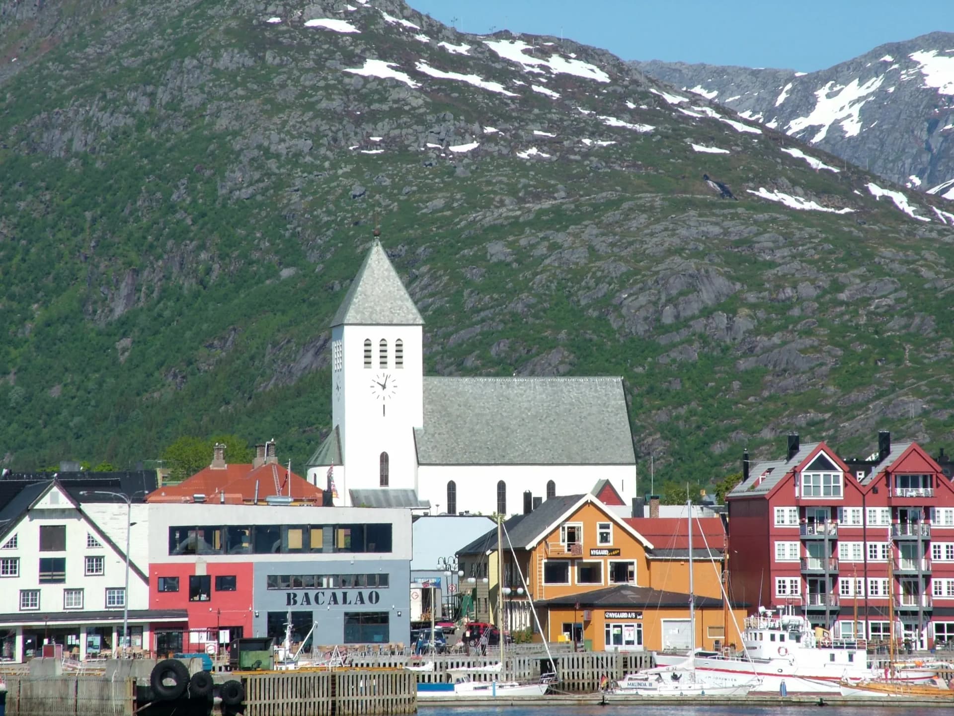 Svolvær kirke og fargerike hus ved havna i Vågan med Lofot-fjell bak